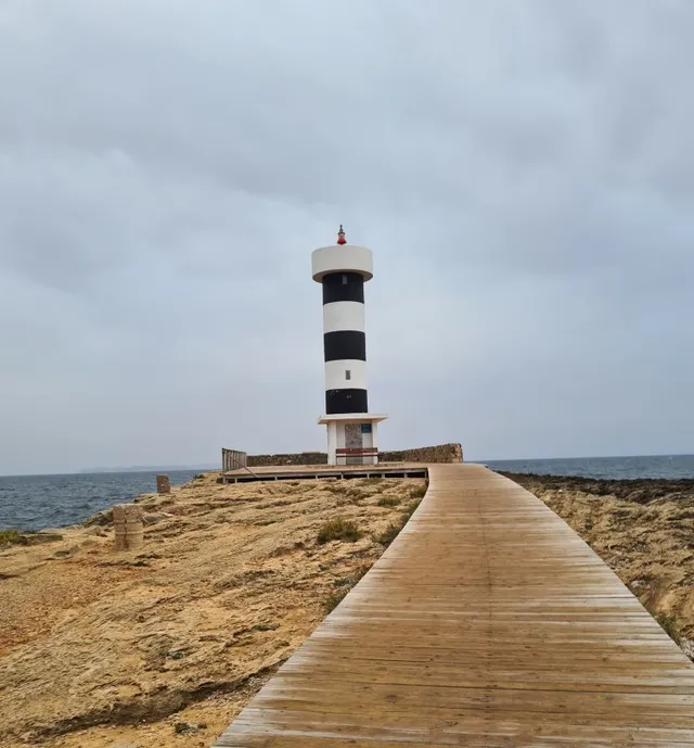 Leuchtturm am Meer mit einem Holzsteg, der auf ihn zuführt